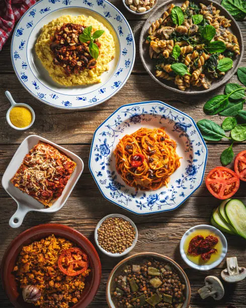 Vegan Mediterranean diet food arrangement, plant based recipes Mediterranean food as vegan Lasagna, Polenta, Spaghetti tomato sauce and Fusilli mushrooms, baked rice and lentils