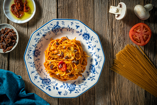 Spaghetti with Tomato Pasta Vegan Italian food plant based recipe Mediterranean diet with ingredients as tomato sauce, cherry tomatoes, mushrooms, dried tomatoes, onion, chili flakes