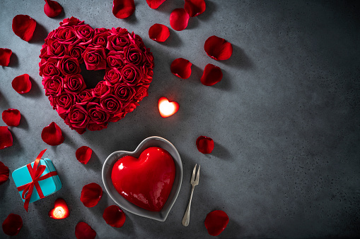 Composition for Valentine's Day with a gift box and a bouquet of roses on a blurred background with bokeh lights.