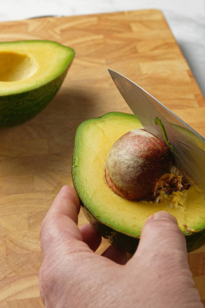istock Avocado being sliced on a wooden cutting board. Close-up. 1366481345