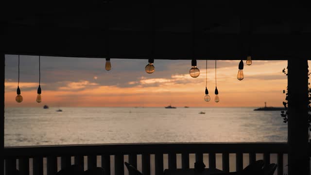 A very cool evening landscape in a summer cafe by the sea. Decorative light bulbs hang on the background of a beautiful sky and sea.