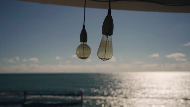 Beautiful light bulbs hang under a canopy on the beach decorating the space on the seashore. An interesting prospect