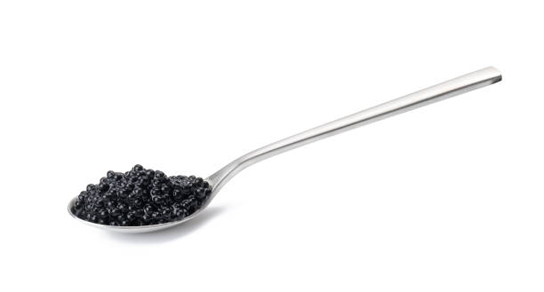 black paddlefish caviar in a metal spoon on a white isolated background black paddlefish caviar in a metal spoon on a white isolated background caviar stock pictures, royalty-free photos & images