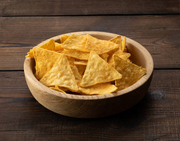 istock triangular nachos with spices in a round wooden bowl. brown table 1366500621