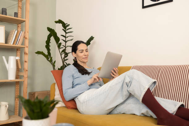 istock Woman enjoying on the sofa and surfing the net 1366501681