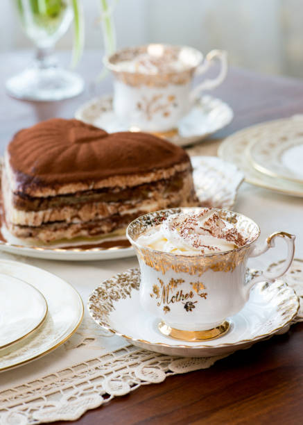 juego de té dorado dorado del día de la madre sobre mesa de madera maciza con pastel de tiramisú en forma de corazón en el fondo - nobody tablecloth cup saucer fotografías e imágenes de stock