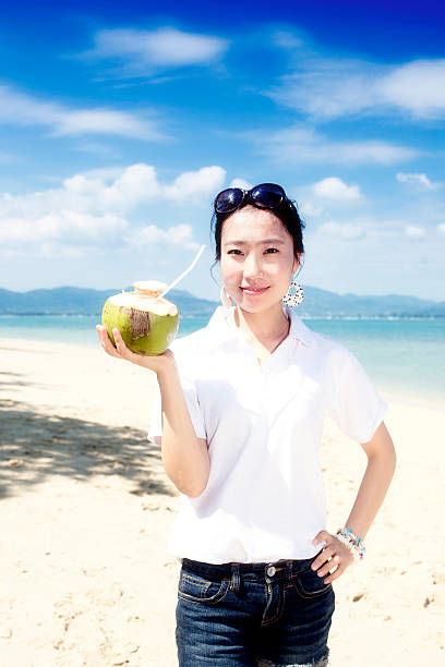 Asian girl drinking coconut on the beach