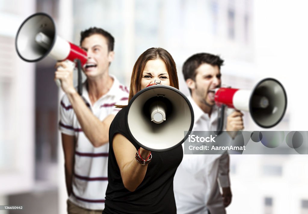 group of employees portrait of a angry  group of employees shouting using megaphones against a city background Megaphone Stock Photo