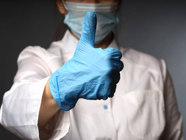 female doctor's hands in nitrile blue gloves show the test okay thumbs up stock photo