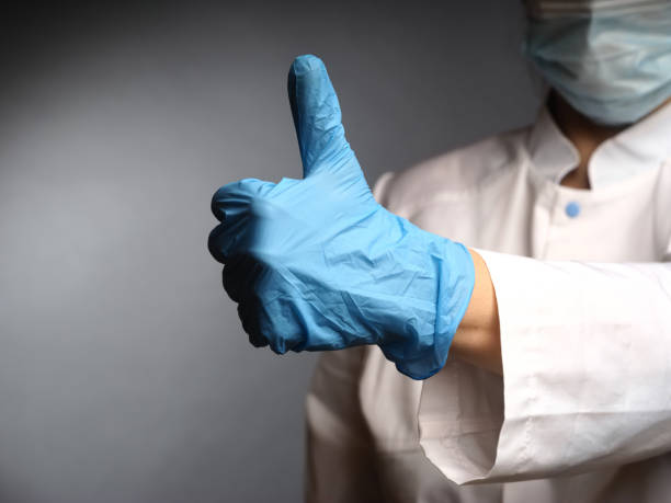 female doctor's hands in nitrile blue gloves show the test okay thumbs up stock photo