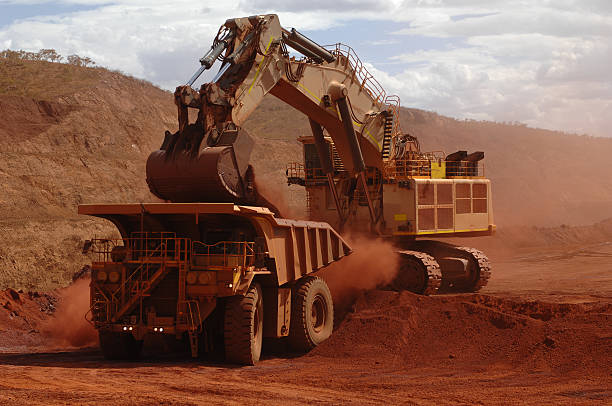 A loader dumps ore and dirt into the rear tray of a large haul truck on a mine site.