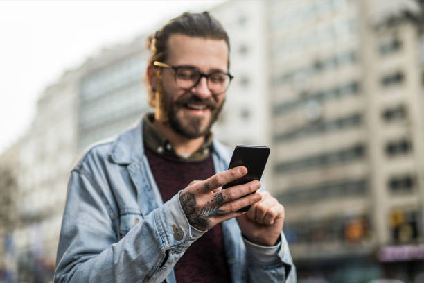 istock Cheerful young man using phone in the city. 1366509754