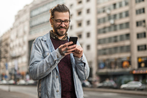 istock Cheerful young man using phone in the city. 1366509765