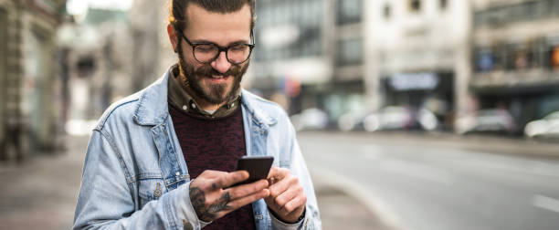 istock Cheerful young man using phone in the city. 1366510063