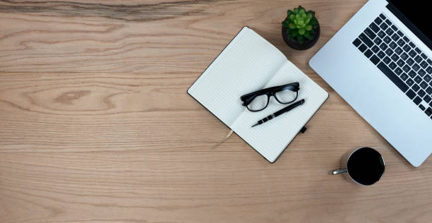 istock Wood office desk table with writing supplies, coffee and laptop for work or study. Top view with copy space in flat lay format. 1366511082
