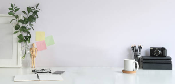 istock Creative designer workplace with camera, books, coffee cup, picture and houseplant on white table. 1366513537
