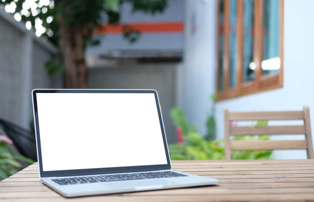 istock Computer laptop with white empty screen on wooden table at outdoor cafe. 1366513553
