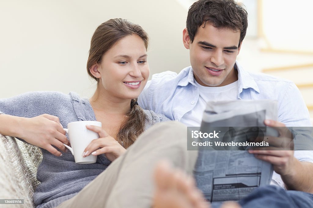 Пара чтение новостей, лежа на диван - Стоковые фото Газета роялти-фри