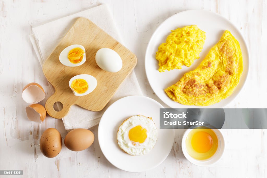 Cooking eggs in deferent way. Cooking eggs in deferent way like boiled egg, fried egg and scrambled egg on wooden table. Top view. Breakfast Stock Photo
