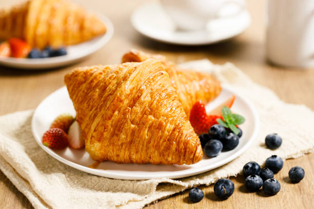 istock breakfast with croissants and fresh berries on wooden table. 1366515349