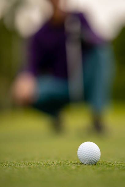 istock Focus on golf ball with golfer blurred in background 1366522571
