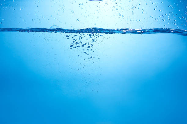 istock Blue background with water bottle falling in and multiplle drops and splashed. Water bubbles texture 1366522643