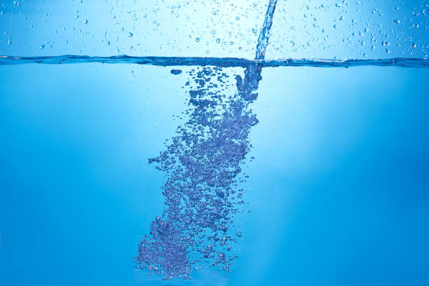 istock Blue background with water bottle falling in and multiplle drops and splashed. Water bubbles texture 1366522726