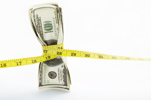 Measuring tape twining several US$100 bills over white background