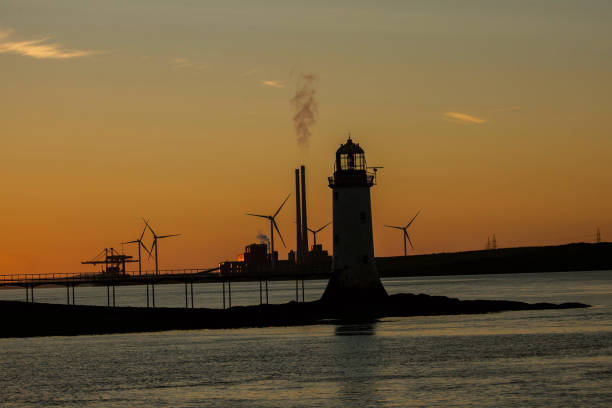 istock Tarbert, Ireland lighthouse with Windmills and sunset in background. 1366529888