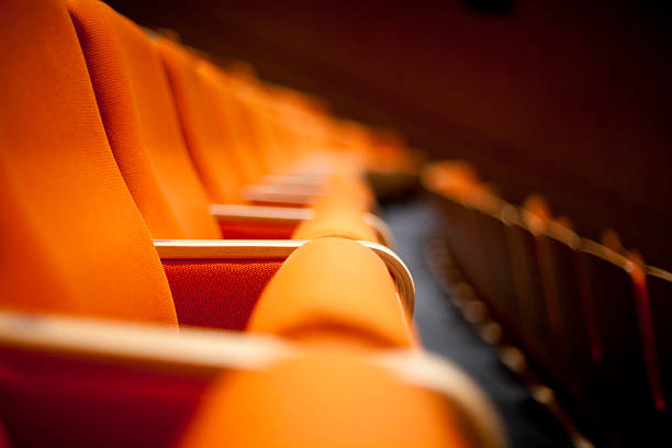 Long row of empty orange seats in a concert hall stock photo