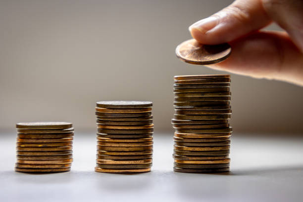 istock Woman's hand placing penny on top of stack 1366533488