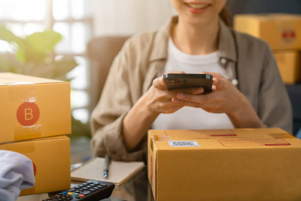 istock Startup small business, woman hand using smartphone with scan QR code on cardboard box delivery for products to send to customers. 1366534590