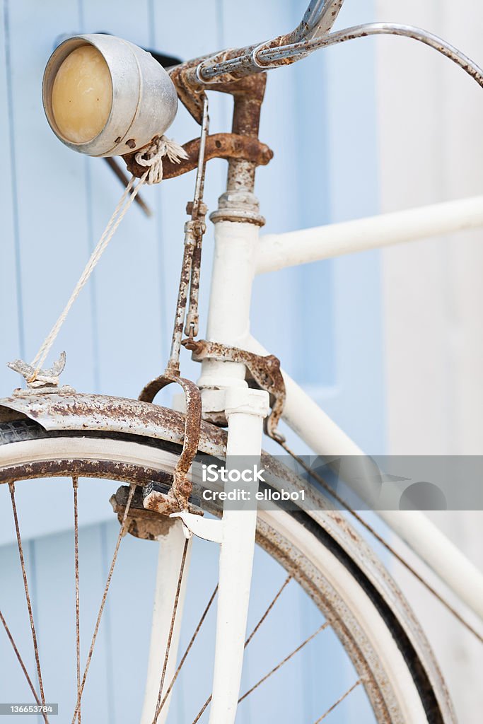 Vieux vélo contre penchée porte bleue. - Photo de Blanc libre de droits