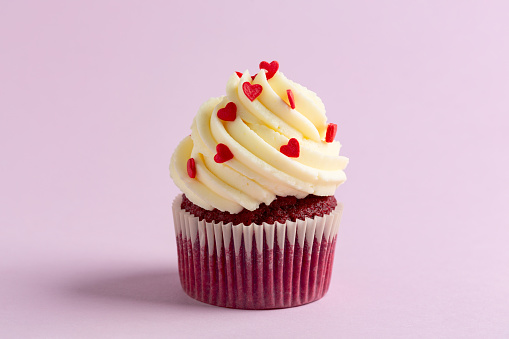 Red velvet cupcake decorated with sugar hearts, copy  space. Concept of sweet pastries for Valentine's Day.