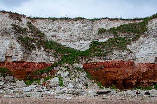 Limestone cliff collapse resembling the letter X due to erosion at Old Hunstanton in Norfolk with grass growing on the rock fall