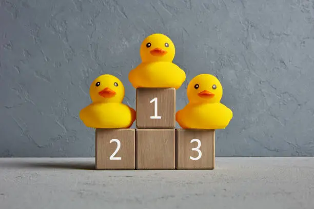 Photo of Rubber ducks ranked on a winner podium with numbers. Business competition or sports championship