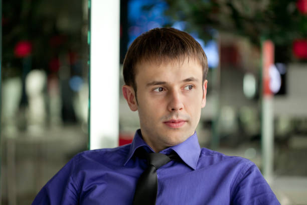 Prosperous young businessman having coffee break at cafe, using smartphone, copy space.Young entrepreneur having tea or coffee in cafe at break.Happy young businessman with cup of tea having breakfast in the cafe.