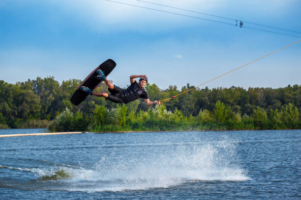 istock Focused wakeboarder jumping with board over calm lake water surface creating splashes 1366546081