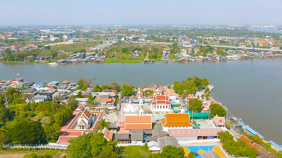 Aerial top view of residential local houses with Phasi Charoen, Chao Phraya canal or river, nature trees, Nonthaburi City, Thailand in urban city town in Asia, buildings.