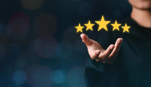 Photo of The customer's hand or the customer holds a star to complete five stars. with copy space five star rating excellent award service rating Satisfaction Concept comment