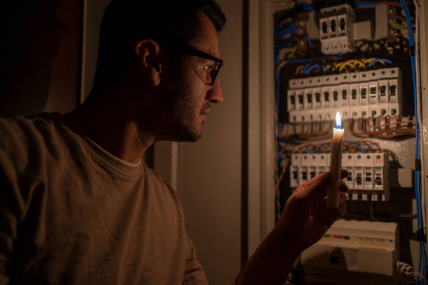 Power Outage Man Checking Home Fuse Box By Candlelight During Power Outage . Blackout Concept. energy crisis photos stock pictures, royalty-free photos & images