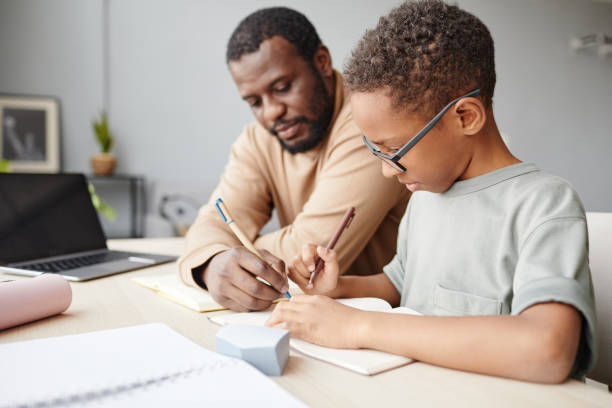 istock Black Boy Studying at Home with Father 1366555020