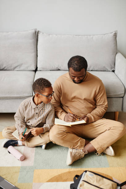 istock Father and Son Studying on Floor 1366555136