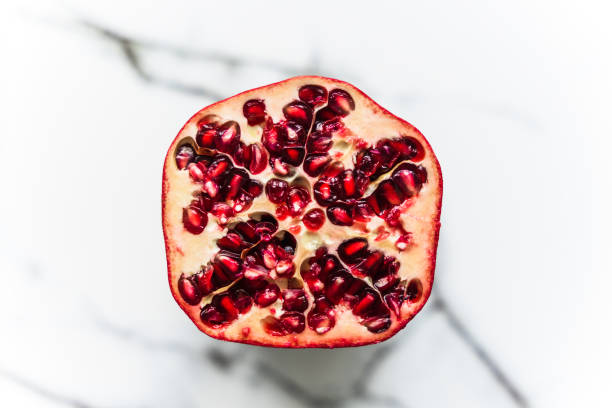 Top view of a halved pomegranate on a marbled background.