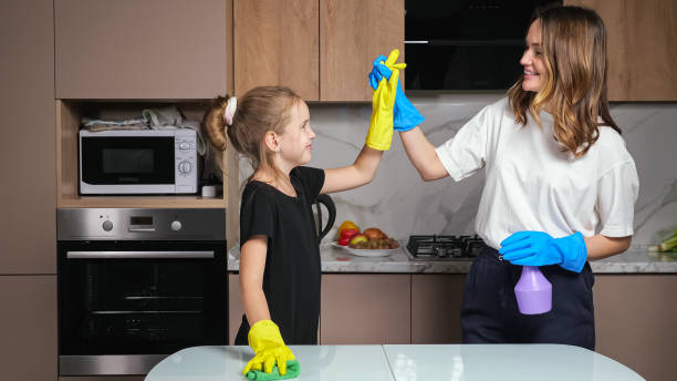 istock Mother and daughter with gloves clean white table in kitchen 1366558910