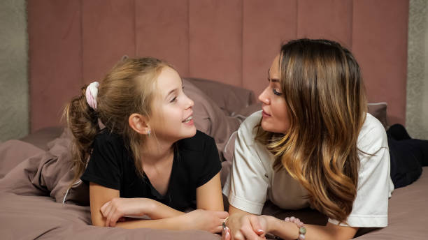 istock Mother and daughter hug lying on soft bed smiling at home 1366558955