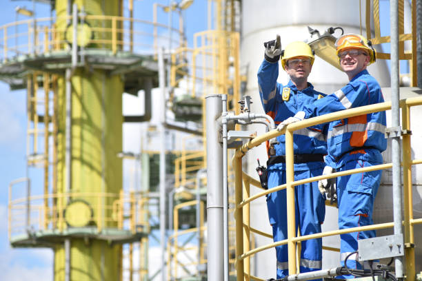 istock teamwork: group of industrial workers in a refinery - oil processing equipment and machinery 1366559100