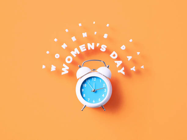 istock Women's Day Message Sitting Above White Alarm Clock On Orange Background 1366559694