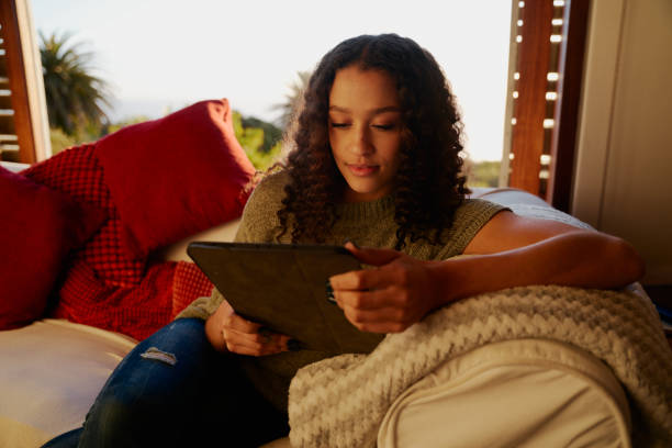 istock Multicultural young adult female centent while watching screen of electronic tablet. Modern apartment, leisure living in daytime 1366560043