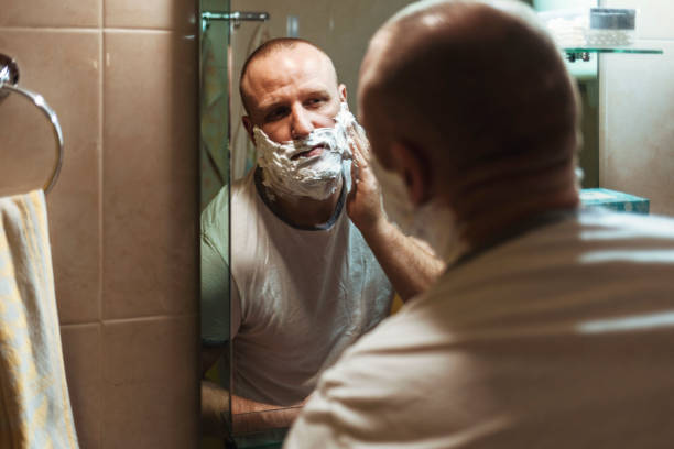 istock Handsome man applying shaving cream, reflection in the mirror. 1366562331
